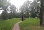 Ein gepflasterter Weg führt zum schmalen Eingang des Denkmals.