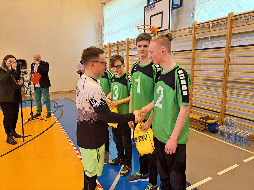 Der Vize-Marschall, ein polnischer Vertreter der Politik gratuliert im Vordergrund Leon, unserem Kapitän der Schulmannschaft. Daneben stehen die anderen Spieler. Alle tragen die grünen Trikots der Schule. Im Hintergrund stehen eine Fotografin und ein Spre